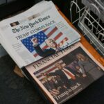 A newspaper sitting on top of a metal dishwasher