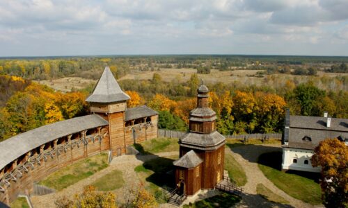 brown and white concrete house on green grass field under white clouds and blue sky during