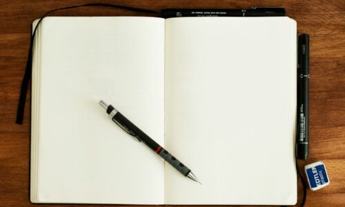black and silver retractable pen on blank book