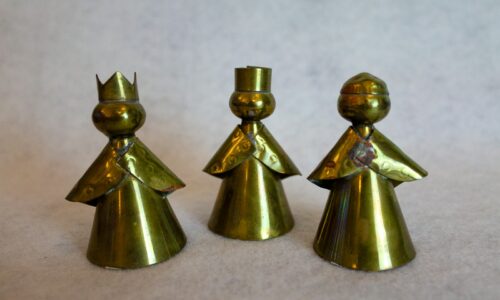 three gold colored metal figures on a white surface
