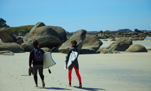 two person with surfboards walking on seashore