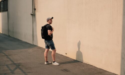man standing beside white concrete wall