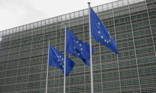 three european flags flying in front of a building