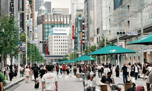 Crowded street with shoppers and modern buildings.