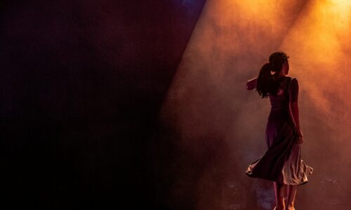 man in black jacket singing on stage