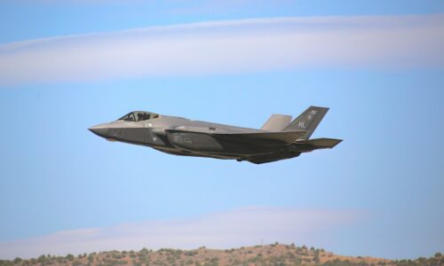 a fighter jet flying through a blue sky