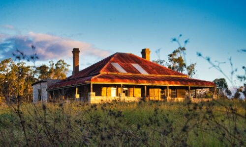 brown and white wooden house near green trees under blue sky during daytime