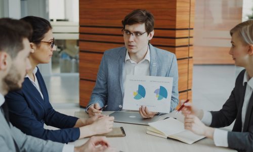 Man presenting charts to colleagues in a meeting.