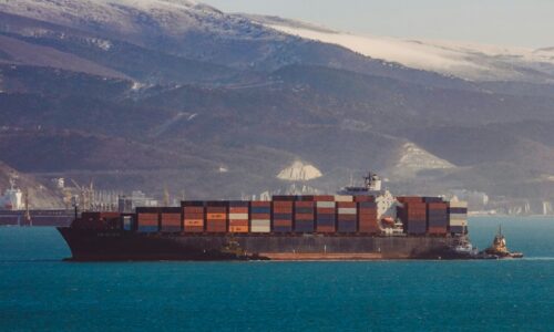 a large cargo ship in the ocean with mountains in the background