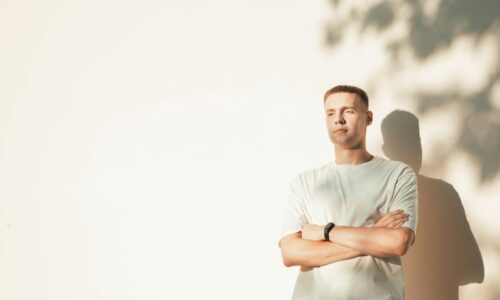 a man standing in front of a white wall with his arms crossed